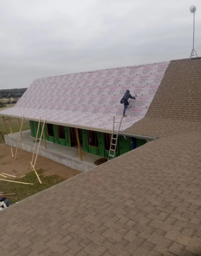 Worker preparing underlayment for a metal roof installation in Kula